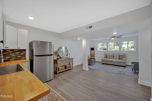 kitchen featuring visible vents, a sink, white cabinetry, freestanding refrigerator, and butcher block counters