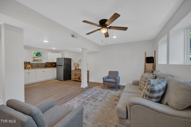 living room featuring light wood finished floors, visible vents, recessed lighting, and baseboards