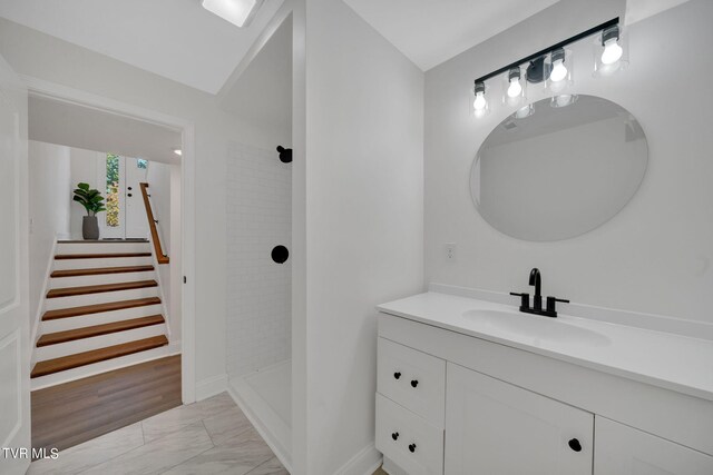 full bathroom featuring marble finish floor, tiled shower, and vanity