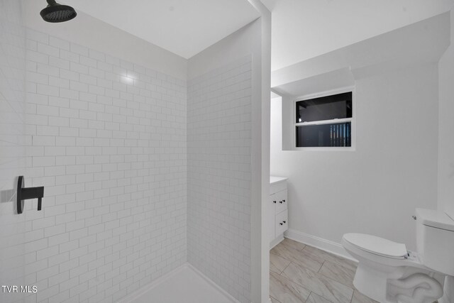 full bathroom with vanity, toilet, baseboards, and tiled shower