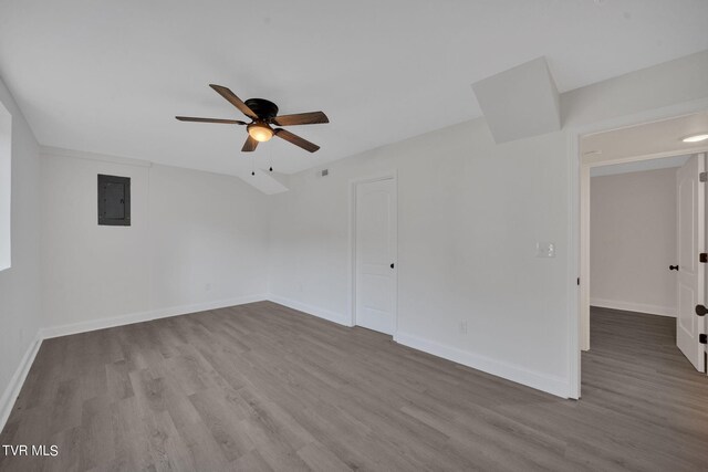 empty room with electric panel, baseboards, and wood finished floors