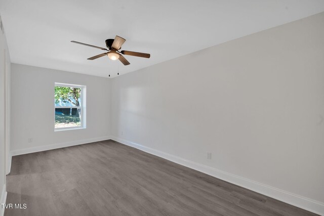 unfurnished room with ceiling fan, baseboards, and dark wood finished floors