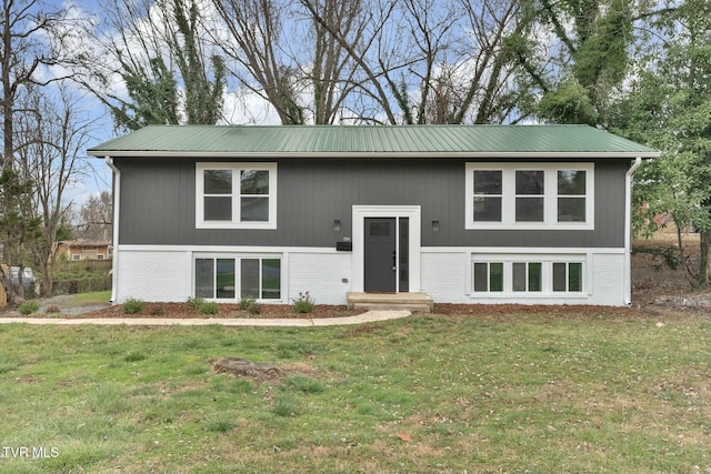 raised ranch featuring brick siding, metal roof, and a front lawn