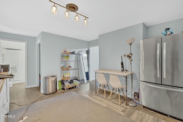 kitchen featuring white cabinetry, light wood-style floors, arched walkways, and freestanding refrigerator