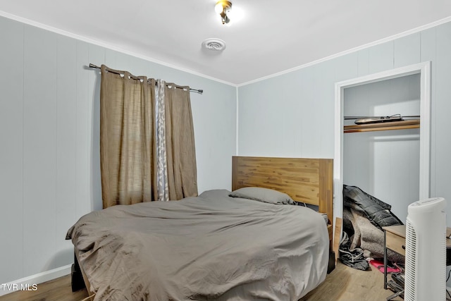 bedroom with visible vents, a closet, wood finished floors, and crown molding