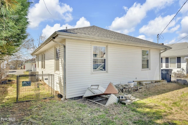 rear view of property with a gate, a yard, and a shingled roof