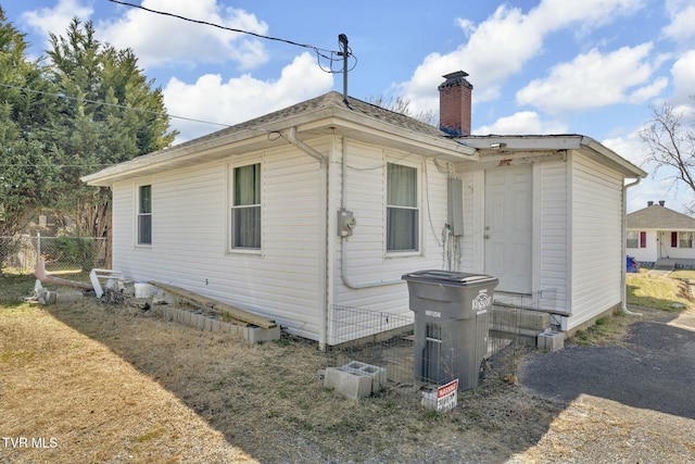 rear view of property featuring a chimney and fence