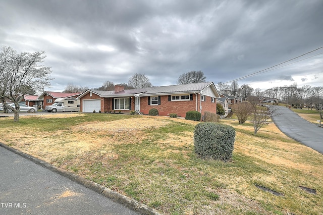 ranch-style house featuring a front lawn, roof mounted solar panels, a garage, brick siding, and a chimney