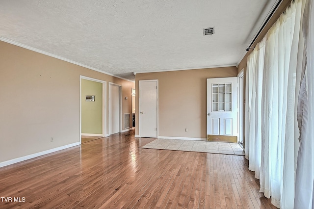 spare room with visible vents, a textured ceiling, baseboards, and wood-type flooring