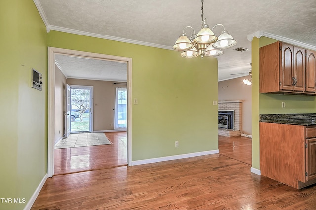 unfurnished dining area featuring a textured ceiling, wood finished floors, and crown molding