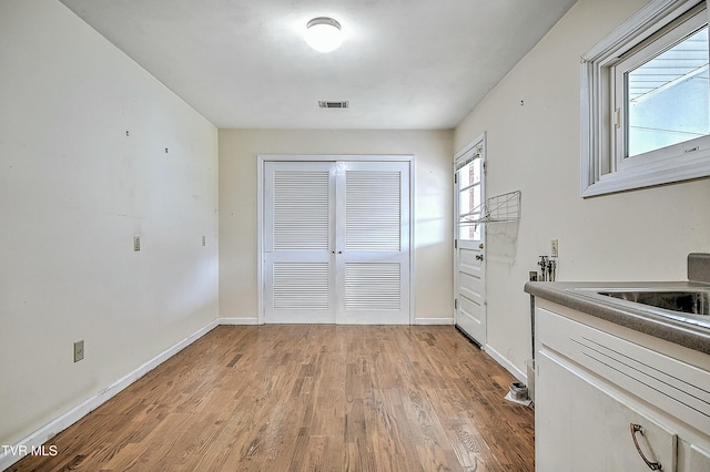 kitchen with light wood-type flooring, visible vents, baseboards, and white cabinetry