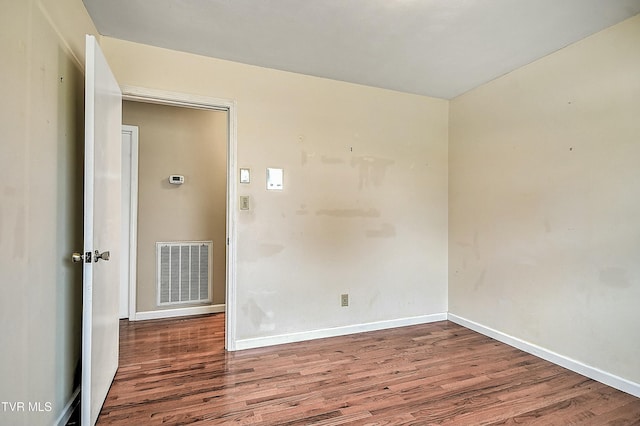 empty room featuring visible vents, baseboards, and wood finished floors