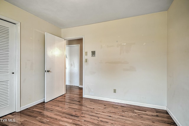 unfurnished bedroom featuring a closet, baseboards, and wood finished floors