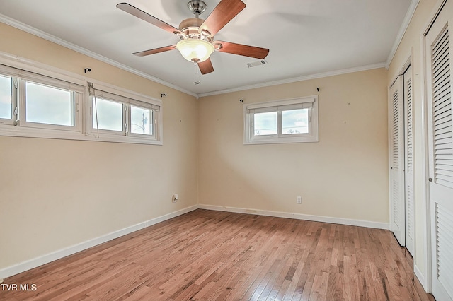 unfurnished bedroom featuring visible vents, light wood-style flooring, a ceiling fan, crown molding, and baseboards