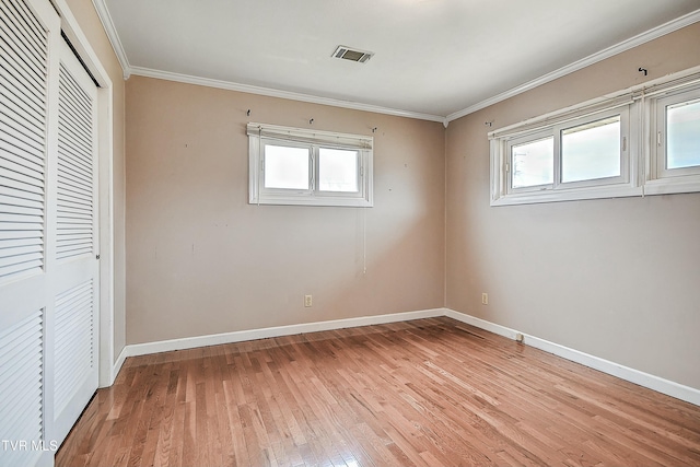 unfurnished bedroom with baseboards, visible vents, light wood finished floors, crown molding, and multiple windows