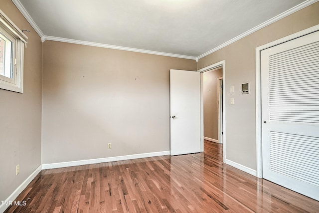 unfurnished bedroom featuring wood finished floors, baseboards, and ornamental molding