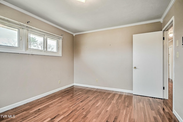 spare room with crown molding, baseboards, and wood finished floors