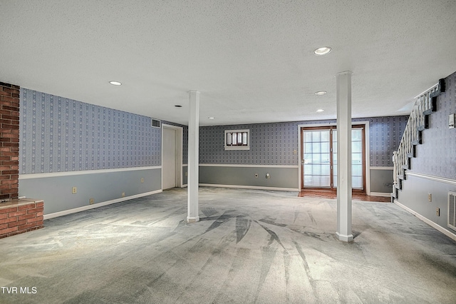 below grade area with carpet, wallpapered walls, wainscoting, stairs, and a textured ceiling