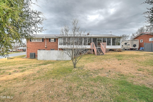 rear view of house with brick siding, central AC, a yard, and a sunroom