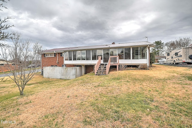 back of house with a yard, brick siding, stairs, and a sunroom