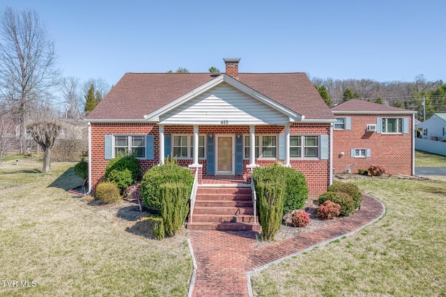 view of front of house featuring a front yard, a porch, a shingled roof, a chimney, and brick siding