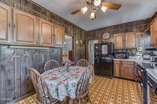 kitchen with black appliances, ceiling fan, wood walls, and light countertops