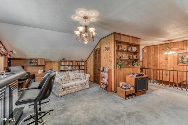 office space featuring wooden walls, lofted ceiling, a textured ceiling, carpet flooring, and ceiling fan with notable chandelier