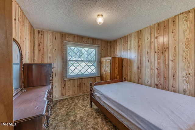 bedroom with wooden walls, a textured ceiling, and carpet