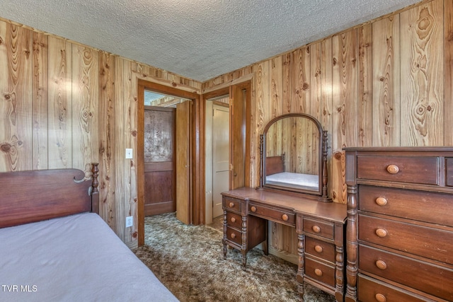 carpeted bedroom with a textured ceiling and wooden walls