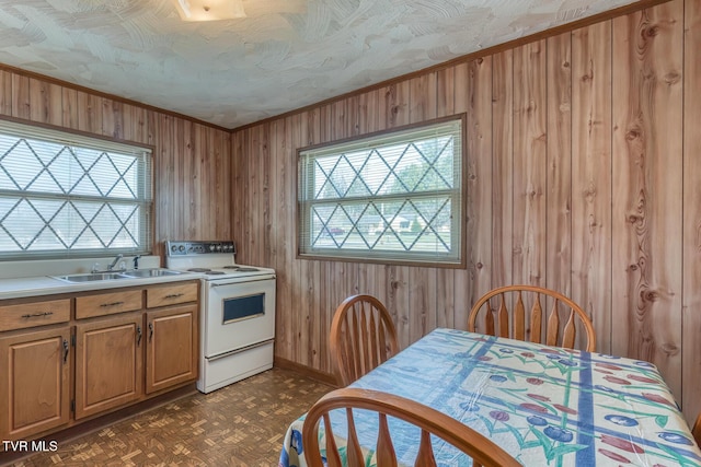 kitchen featuring a sink, wood walls, light countertops, and white range with electric stovetop