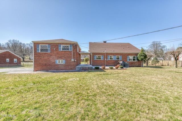 back of property with a yard, brick siding, and fence