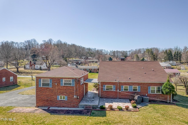 back of property featuring a lawn, a patio, fence, a residential view, and brick siding