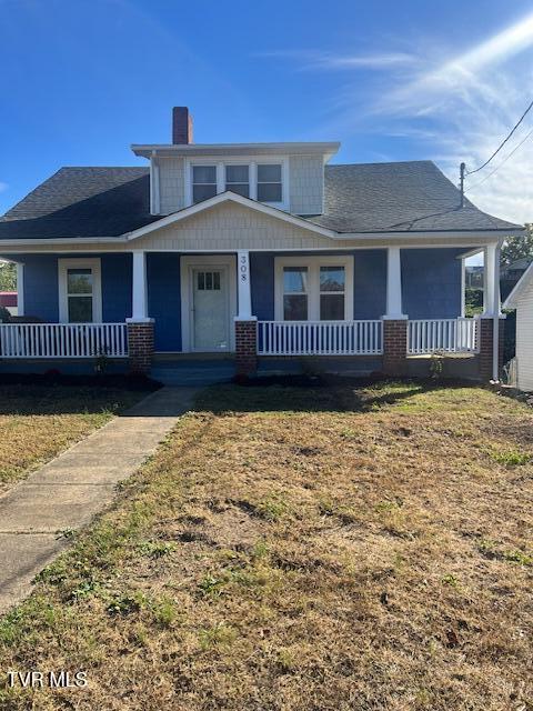 bungalow featuring a porch, a front yard, roof with shingles, and a chimney