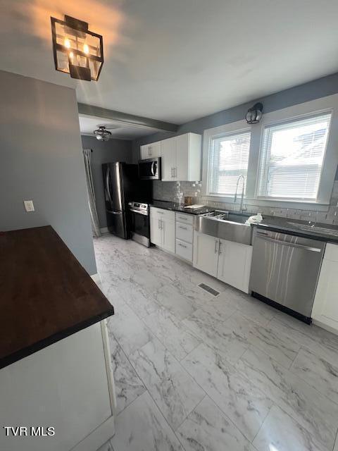 kitchen with visible vents, stainless steel appliances, marble finish floor, dark countertops, and tasteful backsplash