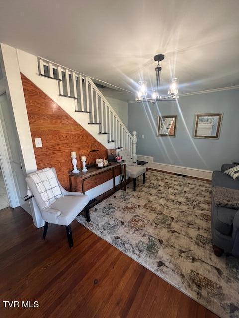 sitting room featuring stairway, a notable chandelier, wood finished floors, and ornamental molding