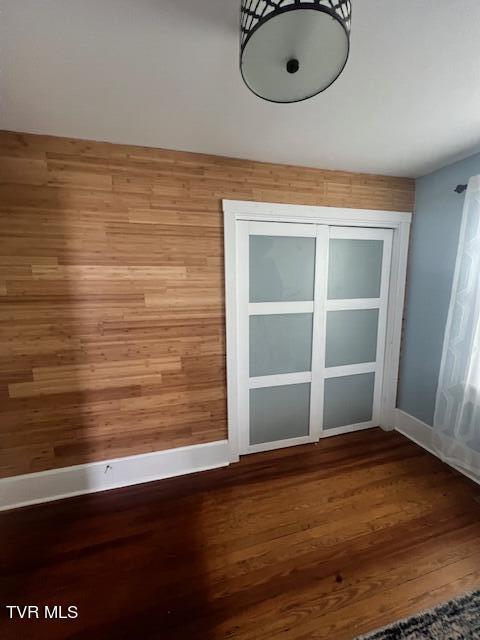 spare room with wooden walls, baseboards, and wood finished floors