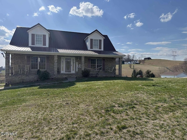 view of front of home featuring metal roof, brick siding, covered porch, and a front lawn