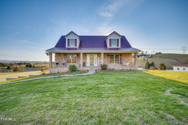 view of front of property with metal roof, brick siding, covered porch, and a front yard