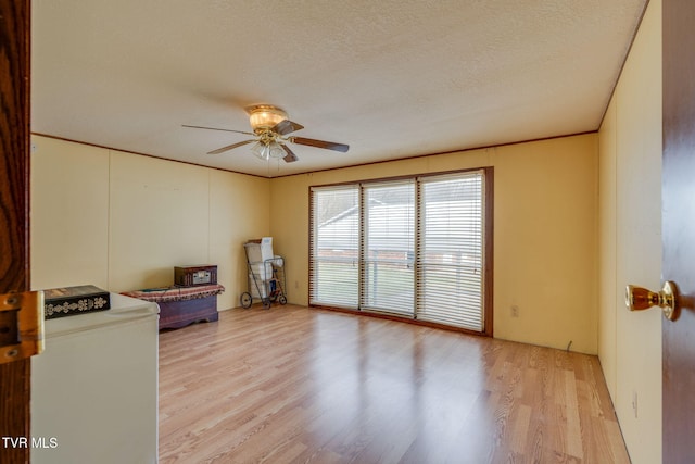 interior space featuring crown molding, a ceiling fan, light wood-type flooring, and a textured ceiling