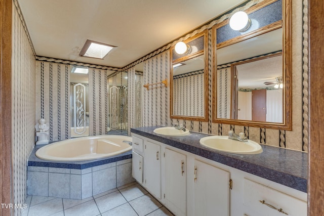 bathroom featuring tile patterned flooring, tiled tub, wallpapered walls, and a sink