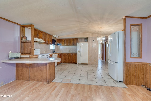 kitchen with white appliances, light wood-style flooring, a peninsula, and brown cabinets