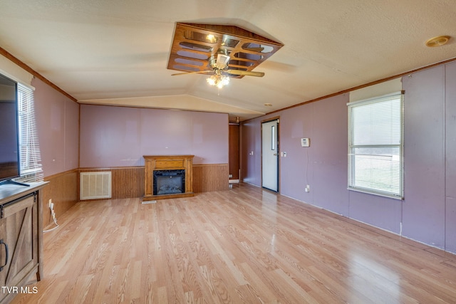 unfurnished living room with visible vents, ceiling fan, a wainscoted wall, lofted ceiling, and light wood-style floors