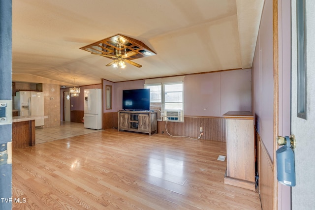 unfurnished living room featuring a wainscoted wall, light wood-style flooring, lofted ceiling, and ceiling fan