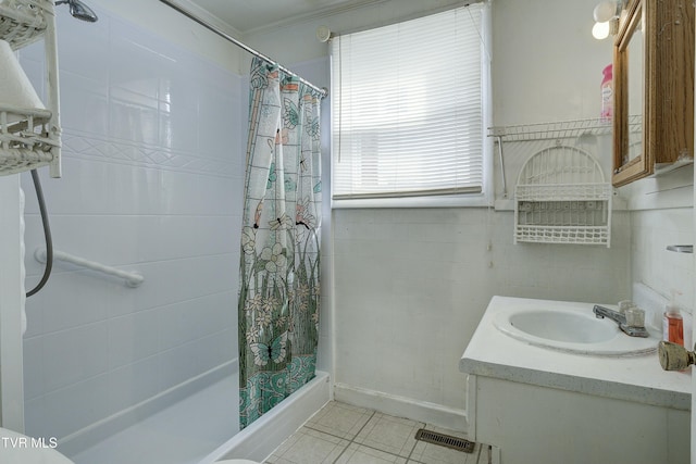 bathroom with tile walls, crown molding, tile patterned flooring, tiled shower, and vanity