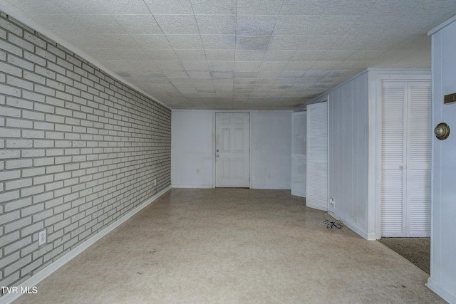 spare room featuring baseboards and brick wall