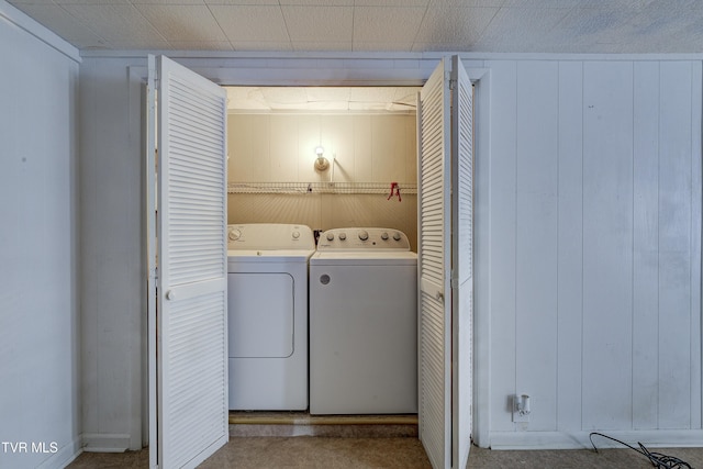 washroom featuring laundry area, wooden walls, and washer and clothes dryer