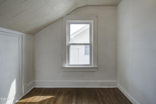 bonus room featuring dark wood-type flooring, baseboards, and vaulted ceiling