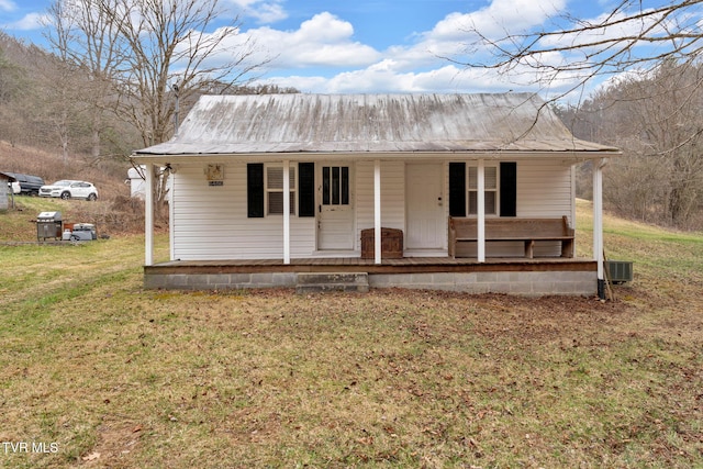 view of front facade with central air condition unit, covered porch, metal roof, and a front yard