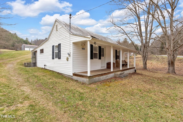 view of side of property featuring a yard, covered porch, and metal roof