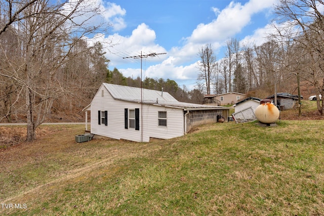 rear view of house with a yard, central AC unit, and metal roof